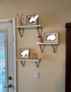 three white shelves with pictures on them against the wall next to a door and window