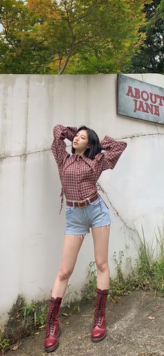 a woman posing in front of a sign with her hands on her head and wearing short shorts