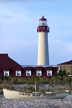 a boat on the sand near a light house with a sign that says cape may point