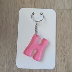 a pink letter shaped keychain sitting on top of a white card