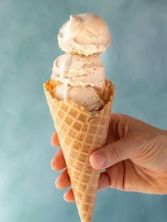 a hand holding an ice cream cone with two scoops