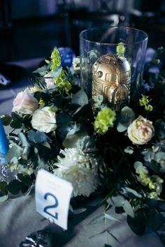 a table topped with a vase filled with lots of flowers next to a number twenty