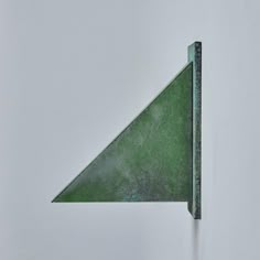 a green triangle shaped object sitting on top of a white wall