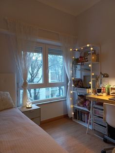 a bedroom with a bed, desk and shelves in it's corner next to a window