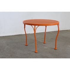 an orange table sitting on top of a cement floor