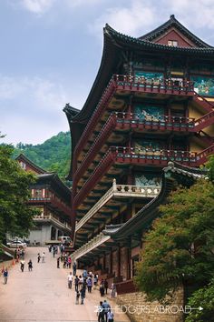 people are walking around in front of a tall building with many balconies on it