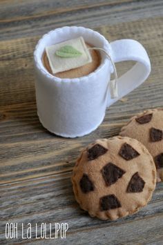 two cookies sitting on top of a wooden table next to a white cup and saucer