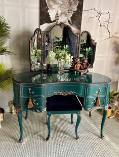 a green desk with two mirrors on top of it and plants in vases next to it