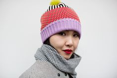 a woman wearing a knitted hat and scarf with a pom - pom