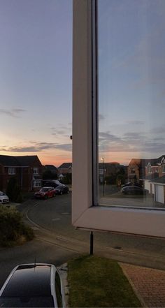 a window with cars parked in front of it and the sun going down behind them