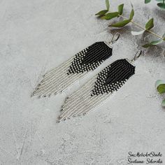 two pairs of black and white beaded earrings with silver chains hanging from the ends