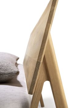 a wooden chair sitting next to a pillow on top of a bed