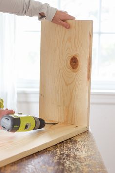 a person using a power drill to attach a piece of wood on top of a table