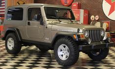 a jeep is parked in a garage with black and white checkered flooring