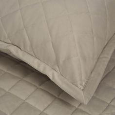 an unmade bed with a white quilted comforter and pillows on top of it