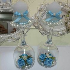 two clear vases with blue flowers in them on a table next to a mirror