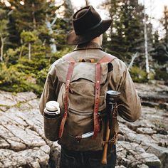 a man with a hat and backpack is walking through the woods