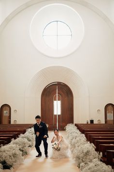 a bride and groom are walking down the aisle in front of pews at their wedding