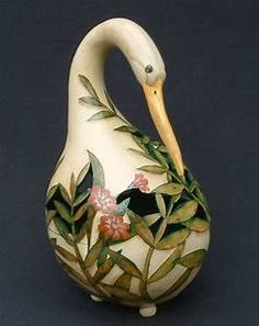 a ceramic swan with flowers and leaves painted on it's body, sitting in front of a black background