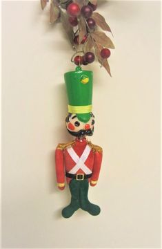 a nutcracker ornament hanging from a tree branch with berries on it