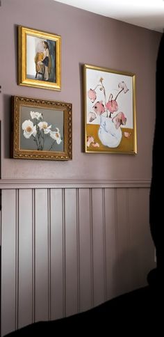 three framed pictures hang on the wall next to a fireplace in a room with wood paneling