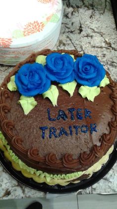 a chocolate cake with blue roses on top and the words later traitor written on it