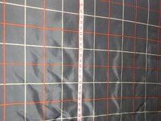 a measuring tape is in front of a gray and orange checkered fabric wallpaper