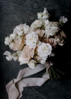 a bouquet of white and pink flowers sitting on top of a gray tablecloth covered floor