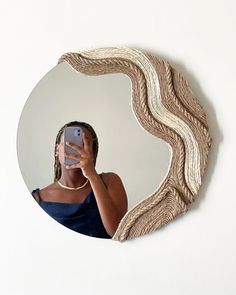 a woman taking a selfie with her cell phone in front of a circular mirror