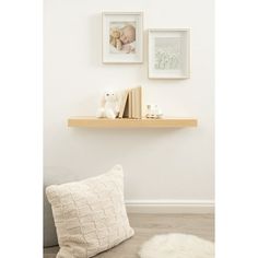 two framed pictures hang on the wall next to a shelf with books and stuffed animals