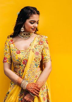 a woman in a yellow sari with her hands on her hips and wearing jewelry