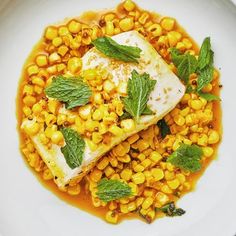 a white plate topped with corn and green leafy garnish