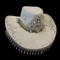 YEEHAW! Beautifully embellished with a variety of rhinestones and pearls, this hat is bound to dazzle the whole saloon! Made from a faux suede, and lined with a beautiful paisley satin, it is as beautiful on the inside as the outside!  Features rope with metal filigree ends, let them hang loose for a wide brim style hat, or tie it up on top for a western style! (see video)  Will fit up to a 60cm head circumference  Also available in other colours and styles. DM for any enquiries 🖤🐎 Note: same Custom Cowgirl Hats With Rhinestones, Cheap Hat Bands For Western-themed Events, Hat With Rhinestone Fringe, Festival Hat With Rhinestones And High Crown, Festival Hats With Rhinestones And High Crown, Elegant Embellished Hats For Festival, Elegant Rhinestone Hats For Festival, Elegant Rhinestone Festival Hats, Boho 2024