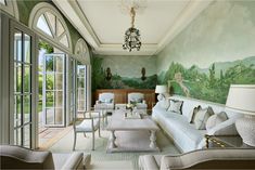 a living room filled with furniture and a painting on the wall behind glass doors that leads to an outside patio