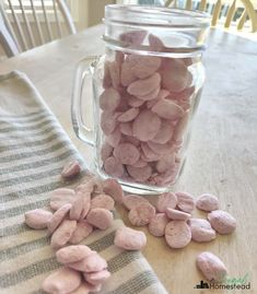 a jar filled with pink marshmallows sitting on top of a wooden table