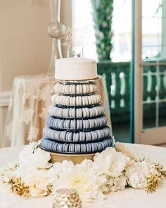 a blue and white cake sitting on top of a table next to some flower arrangements