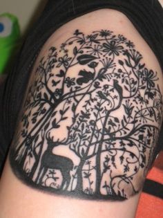 a person with a tattoo on their arm has a deer and tree in the background