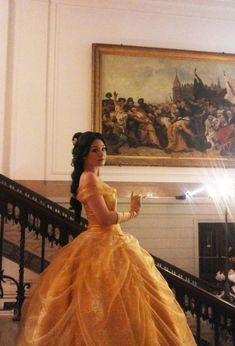 a woman in a yellow dress is standing on the stairs and looking at something behind her