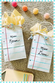 two paper bags with writing on them are sitting on the floor next to some pom poms