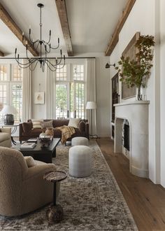 a living room filled with furniture and a chandelier hanging from the ceiling next to a fire place