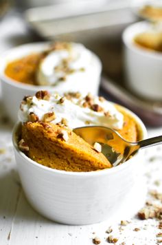 two bowls filled with dessert on top of a white table next to other plates and spoons