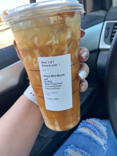 a woman is holding up a cup of iced tea in her hand while sitting in the car