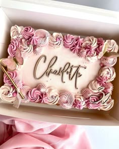 a cake in a box with the word charlotte written on it and pink flowers all around