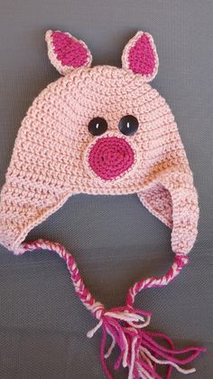 a crocheted hat with ears and eyes is shown on a gray surface,