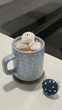 a cup of hot chocolate with marshmallows in it on a white table