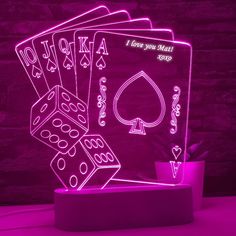 four playing cards and dice are illuminated in purple light