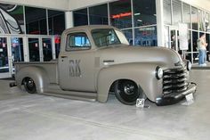 an old gray truck parked in front of a building