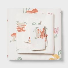 an assortment of napkins and place mats on a white tablecloth with colorful floral designs