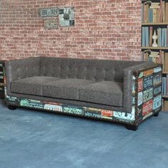 a couch sitting in front of a brick wall next to a book shelf filled with books