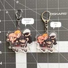 two keychains with anime characters on them sitting on top of a checkered table